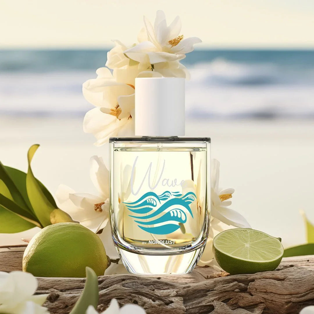 Parfumflakon mit Meereswellen-Design vor Strand, weißen Blüten und Limetten