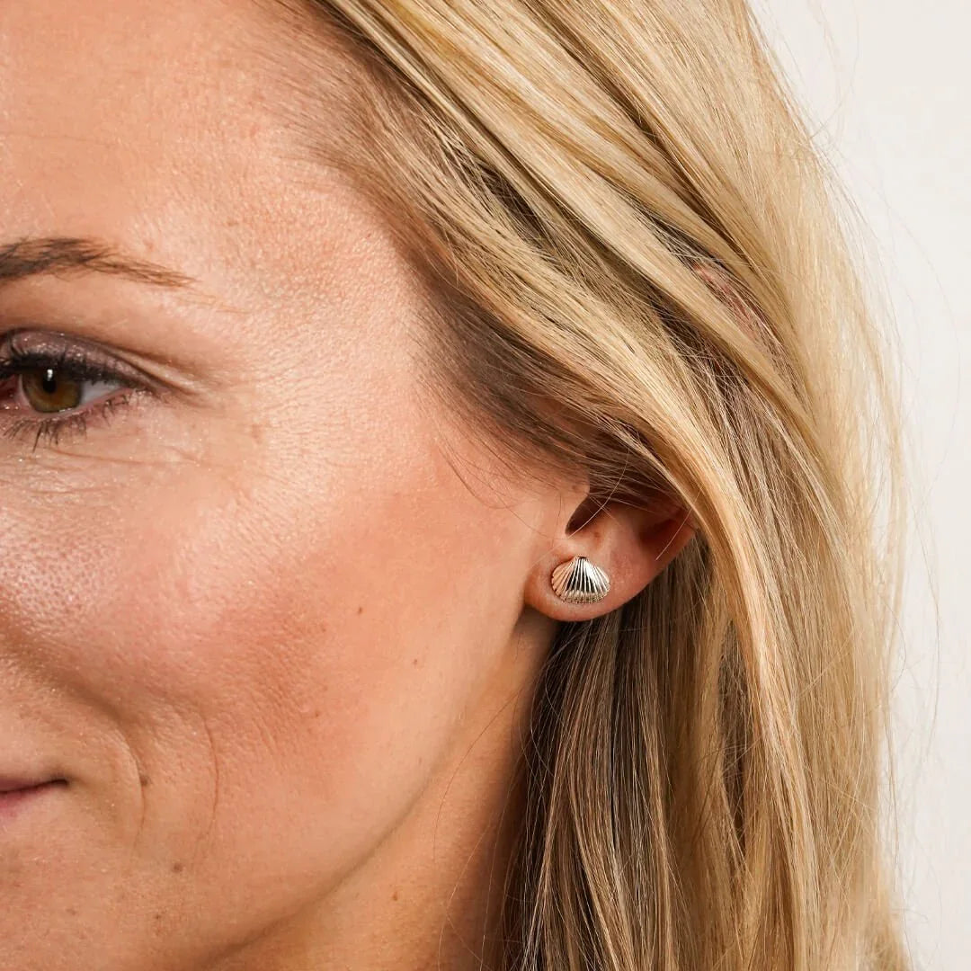 Ohrstecker in Herzmuschel-Form aus Silber am Ohr einer Frau, maritimer Schmuck