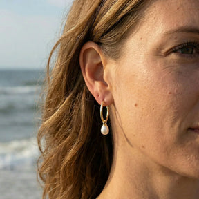 Damen-Ohr mit goldener Creole und weißem Perlenanhänger am Strand, maritimer Schmuck