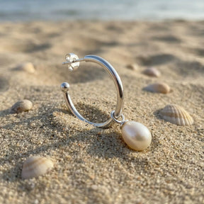 Creole Ohrring aus Silber mit Perlenanhänger am Strand mit Muscheln