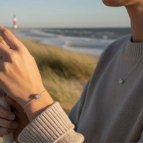 Frau mit Anhänger Strahlender Knoten aus Silber am Strand, maritimer Schmuck im Fokus