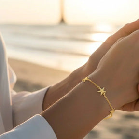 Goldenes Armband mit Seestern-Anhängern am Handgelenk, maritimer Schmuck am Strand