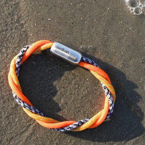 Maritimes Armband aus geflochtenem Tau, orange und schwarz, am Sandstrand liegend