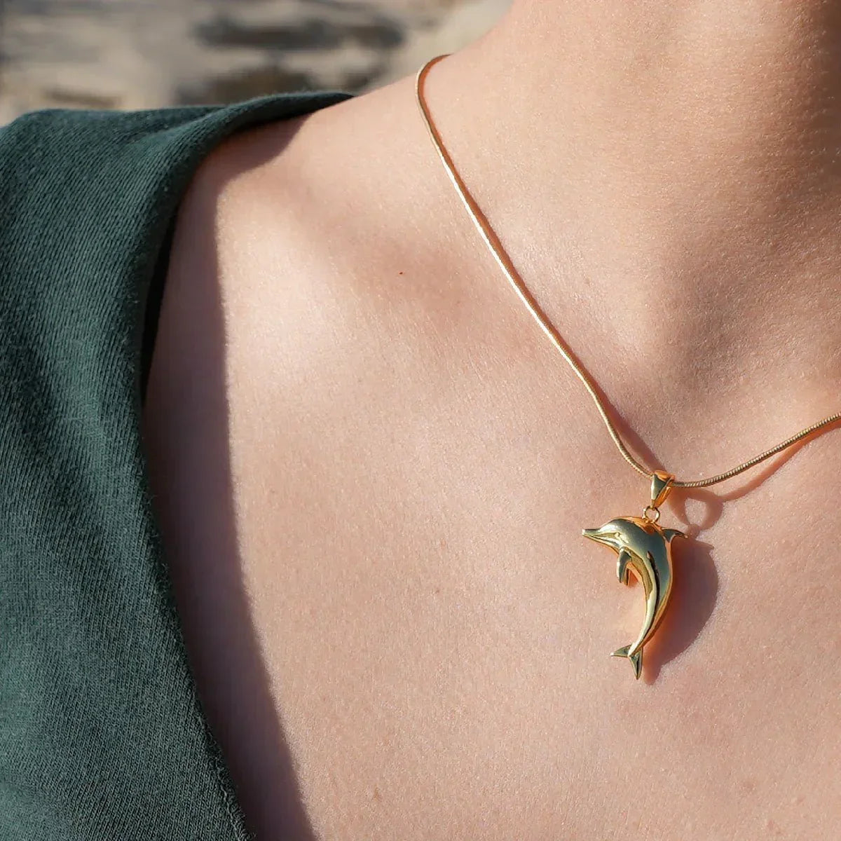 Goldene Delfin-Kette, maritimer Schmuckanhänger, getragen am Hals, Nahaufnahme