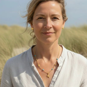 Frau mit goldener Kette und Seestern-Anhänger, maritimer Schmuck am Strand