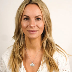 Frau mit langer blonder Haare trägt eine silberne Muschelkette im maritimen Stil