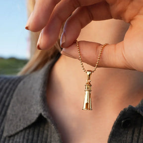 Goldene Halskette mit Leuchtturm-Anhänger, maritimer Schmuck am Hals einer Frau
