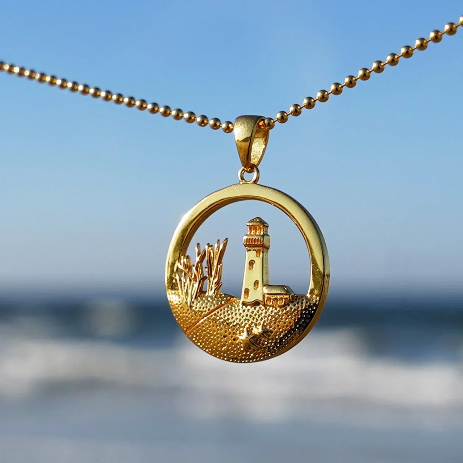 Goldener Kettenanhänger mit Leuchtturm und Dünen, maritimer Schmuck am Strand