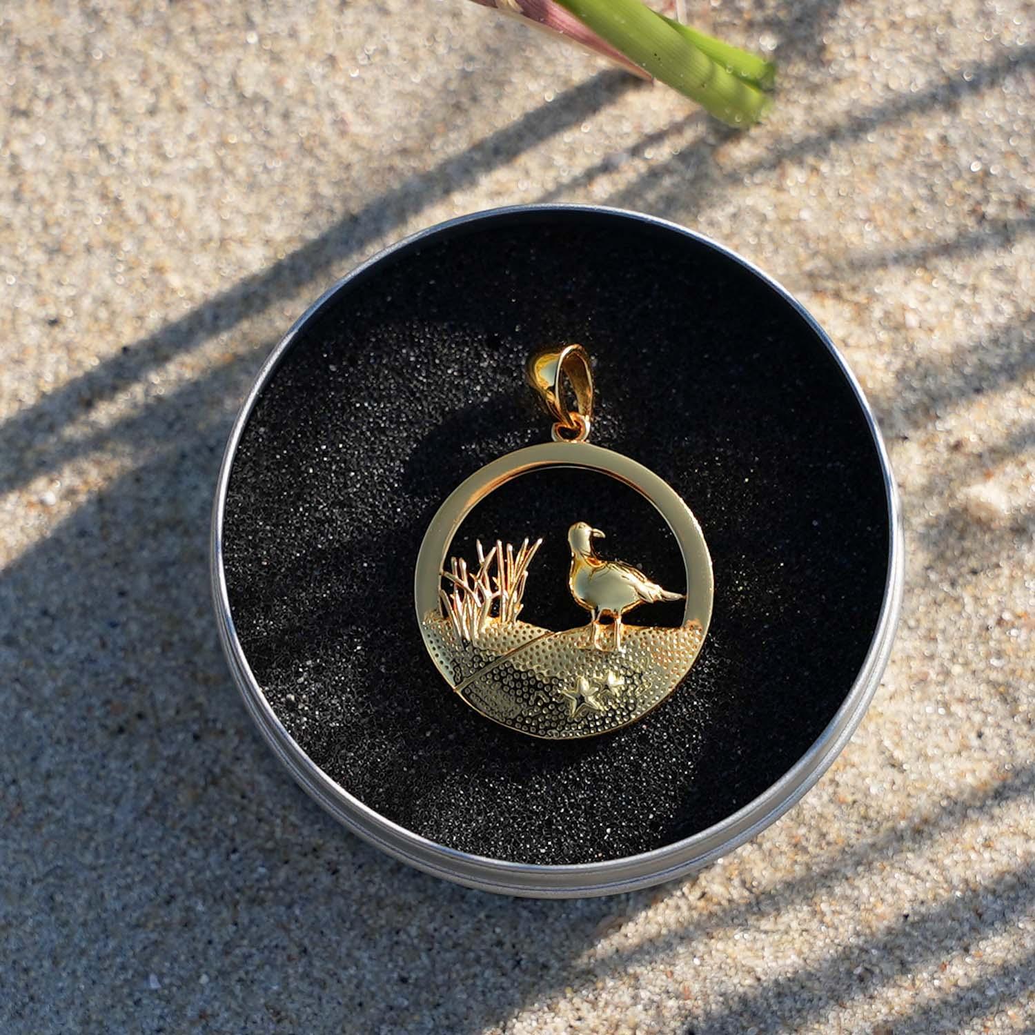 Goldener Anhänger mit Möwe und Dünenmotiv im Sand, maritimer Schmuck für Strandliebhaber