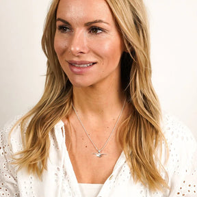 Frau mit maritimer Silberkette, Möwen-Anhänger, weißes Oberteil, Schmuck am Hals