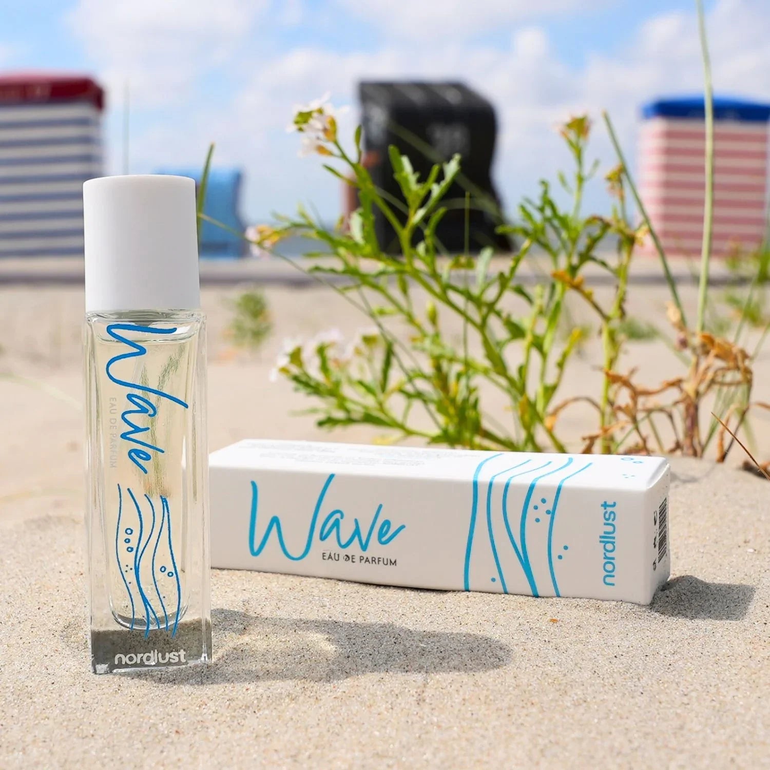 Wave Eau de Parfum 15ml auf Sand mit Strandpflanzen und Strandkörben im Hintergrund