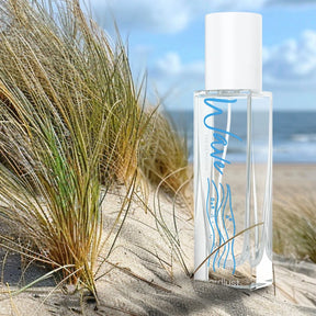Parfümflakon Wave Eau de Parfum 15ml im Sand mit Dünen und Meer im Hintergrund