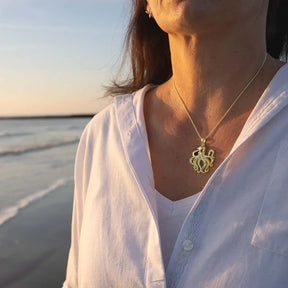 Frau mit goldener Oktopus-Kette am Strand bei Sonnenuntergang, maritimer Schmuck
