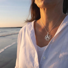 Silberne Oktopus-Kette am Hals einer Frau am Strand bei Sonnenuntergang