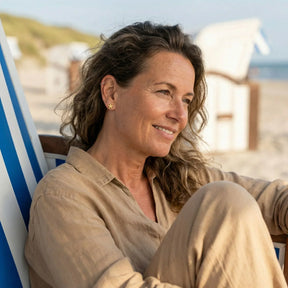 Frau mit goldenen Seestern-Ohrsteckern am Strand, maritimer Schmuck, Sommer