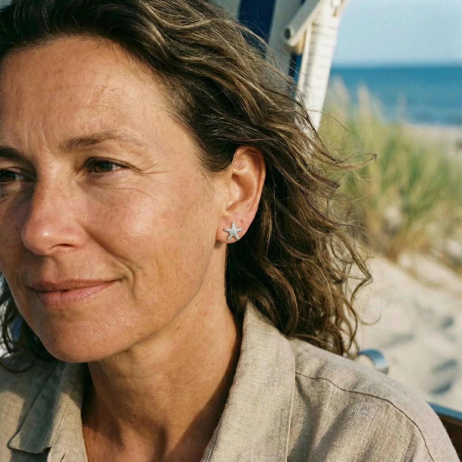 Frau mit silbernem Seestern Ohrstecker am Strand, maritimer Schmuck, Küstenstil