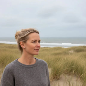 Frau mit silbernen Ohrsteckern am Strand, maritimer Schmuck, Dünen und Meer im Hintergrund