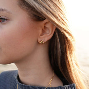 Goldener Seestern Ohrstecker am Ohr einer Frau, maritimer Schmuck, Strandstil