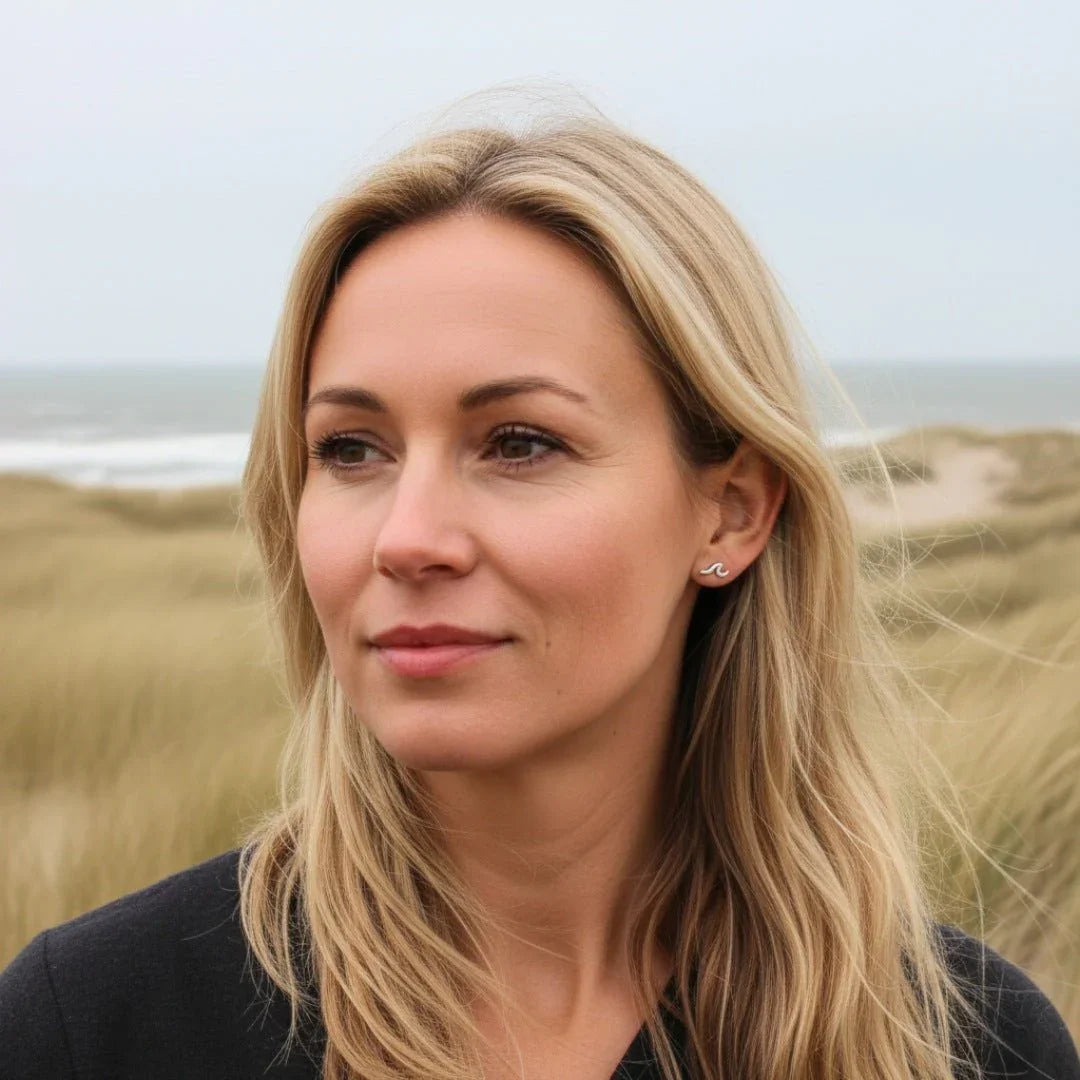 Frau mit silbernem Wellen-Ohrstecker am Strand, maritimer Schmuck, Naturkulisse