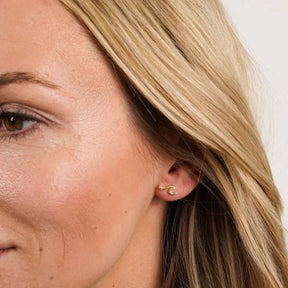 Damen-Ohrstecker in Wellenform aus Gold am Ohr, maritimer Schmuck