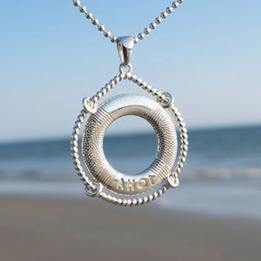 Silberner Rettungsring-Anhänger mit Gravur AHOI, maritimer Schmuck am Strand vor dem Meer