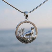 Silberner Seehund-Anhänger mit maritimem Motiv, Kette vor unscharfem Meer-Hintergrund