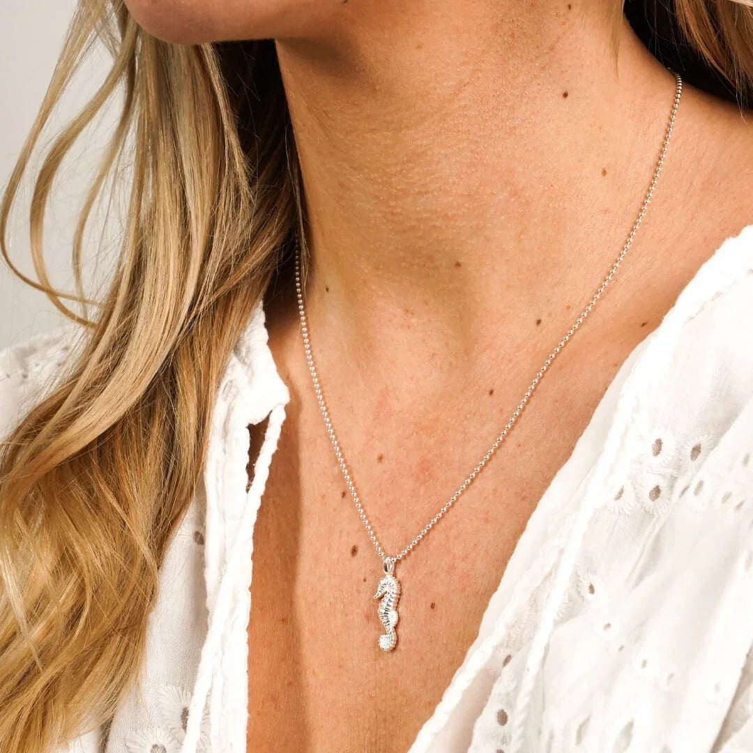 Silberne Halskette mit Seepferdchen-Anhänger, getragen zu weißer Bluse, maritimer Schmuck