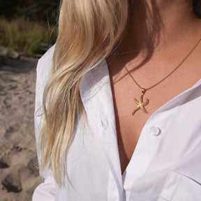 Frau mit goldener Seestern-Kette am Strand, maritimer Schmuck, Sommermode