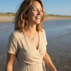 Frau am Strand mit silbernem Seestern-Anhänger, maritimer Schmuck im Sonnenlicht