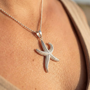 Silberne Seestern-Halskette als maritimer Schmuckanhänger auf gebräunter Haut