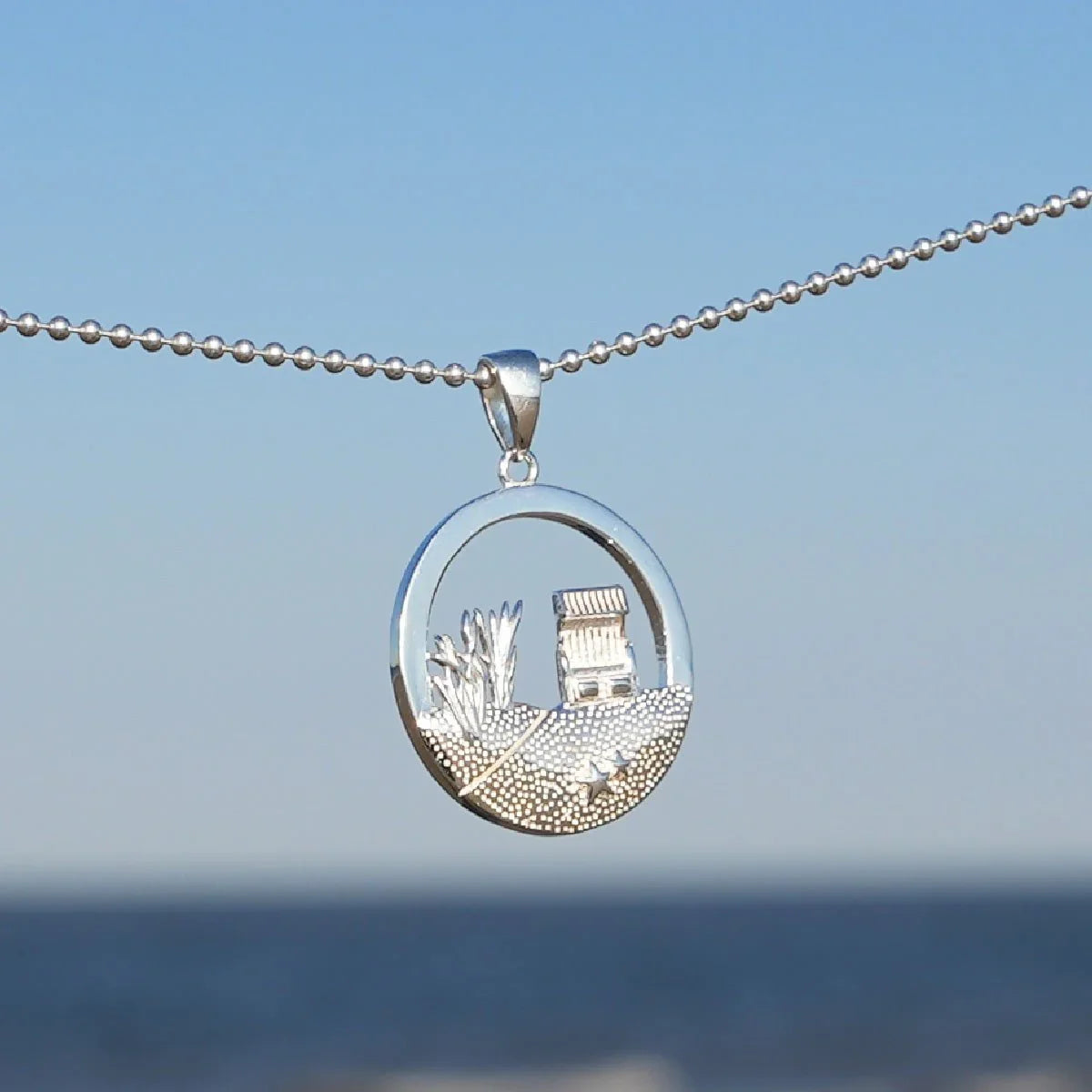 Silber Anhänger mit Strandkorb, Dünen und Seestern Motiv vor blauem Meereshintergrund