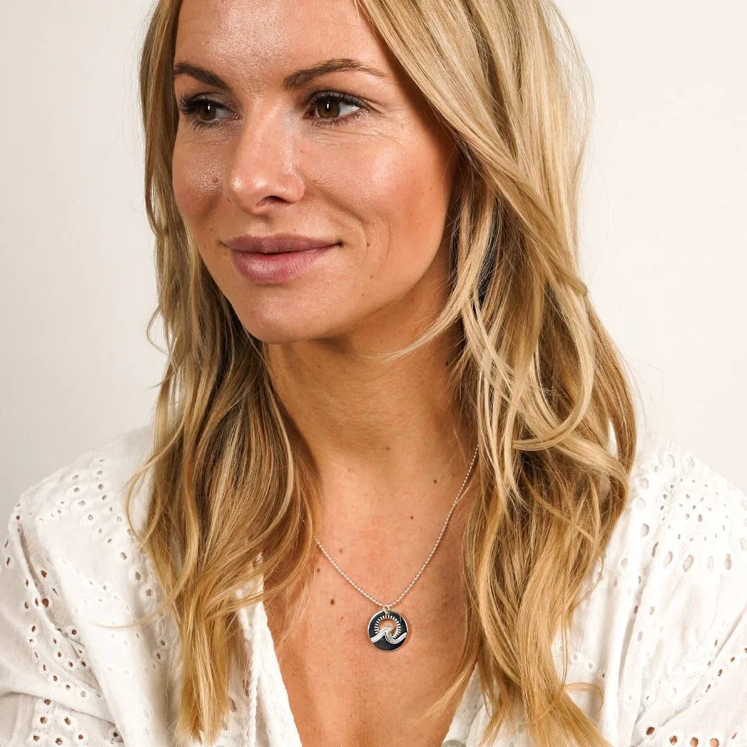 Frau mit rundem Silberanhänger mit Wellenmotiv am Hals, maritimer Schmuck